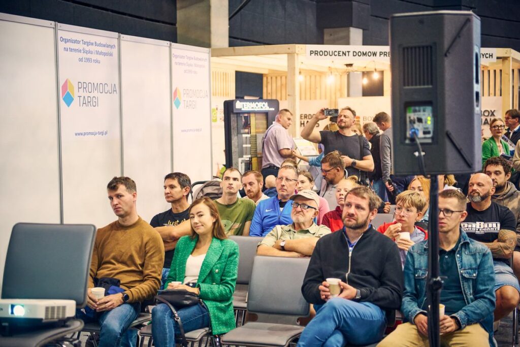 Publiczność podczas prelekcji, w tle logo Promocja Targi